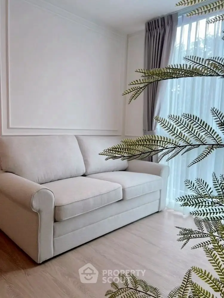 Cozy living room with elegant sofa and natural light through sheer curtains.