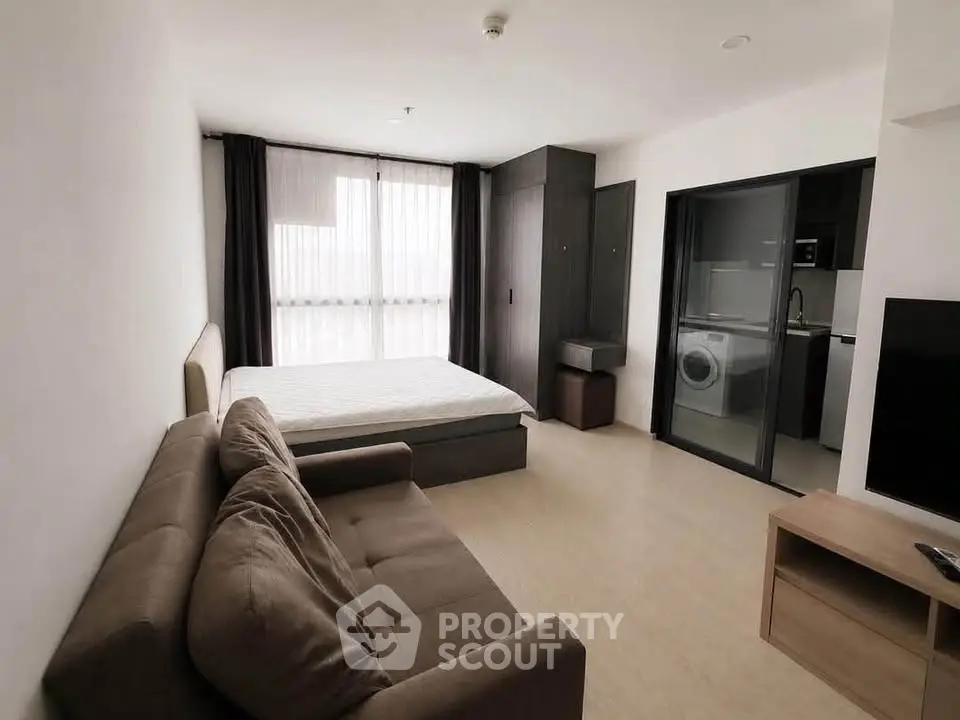 Modern studio apartment with cozy living area and sleek kitchen appliances.