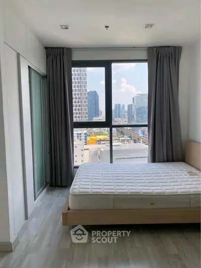 Modern bedroom with large window offering stunning city views in a high-rise apartment.