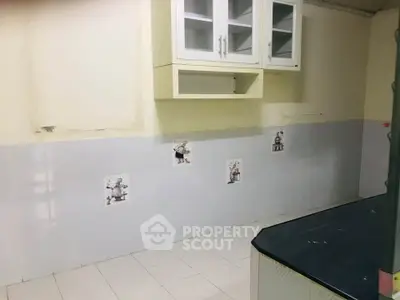 Spacious kitchen with tiled walls and ample storage cabinets, ideal for culinary enthusiasts.