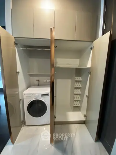 Modern laundry area with built-in storage and washing machine in sleek apartment.