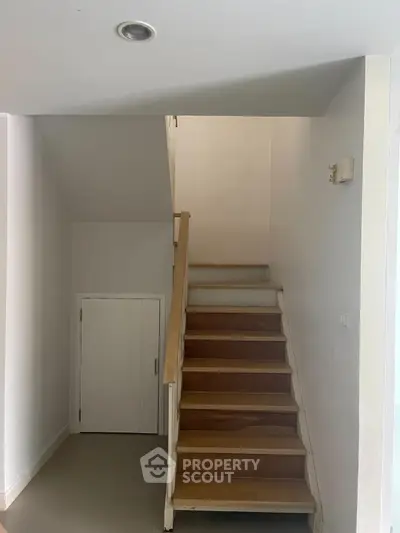 Minimalist staircase with wooden steps and white walls in modern home interior