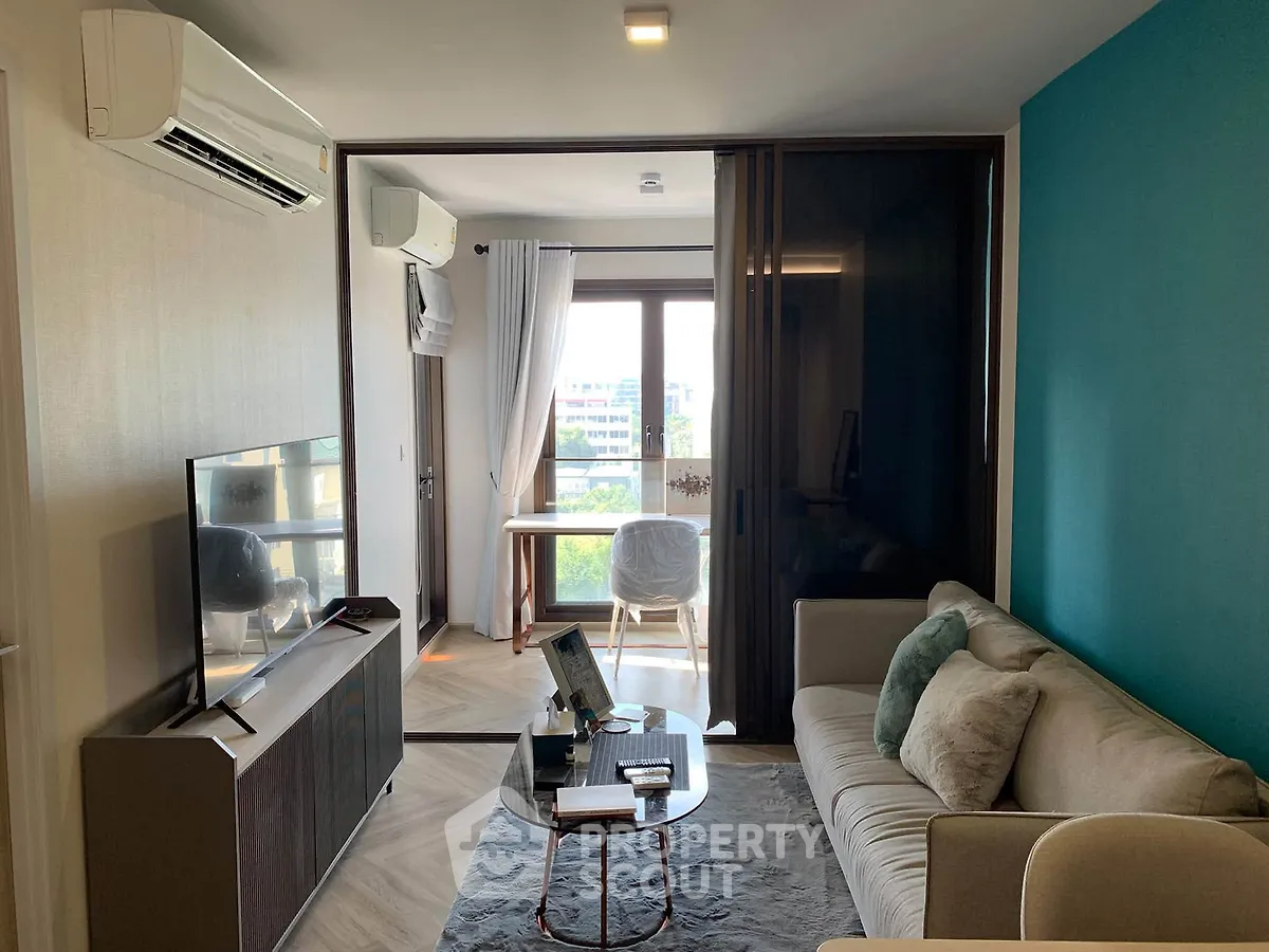 Modern living room with sliding glass doors leading to a bright study area and balcony view.