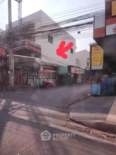 Street view of commercial building with nearby convenience store and street vendor.