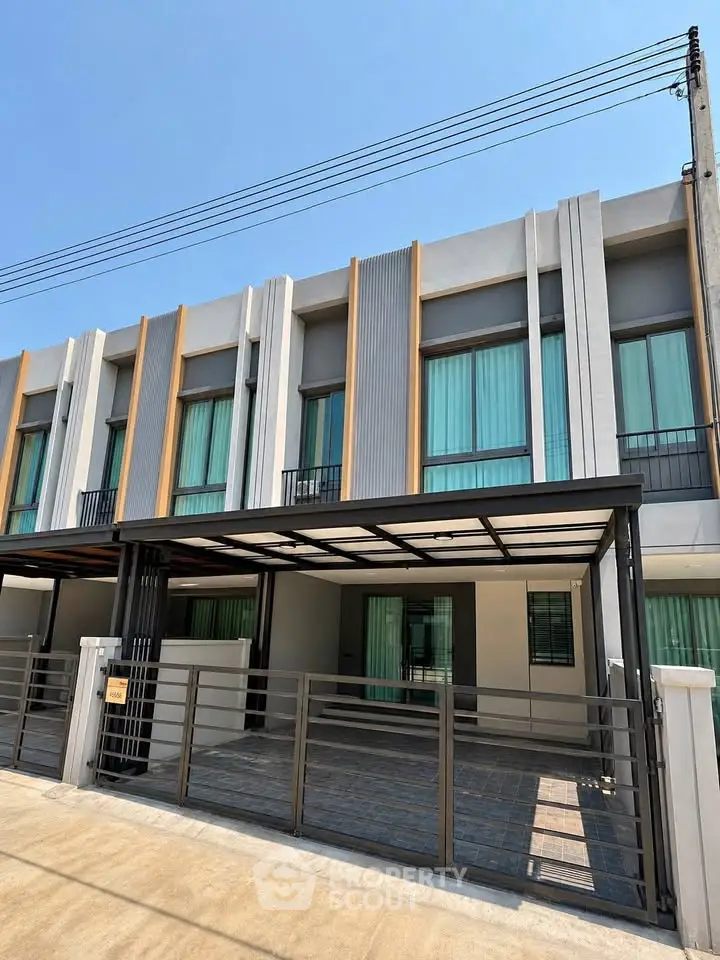 Modern townhouse exterior with sleek design and large windows under a clear blue sky.