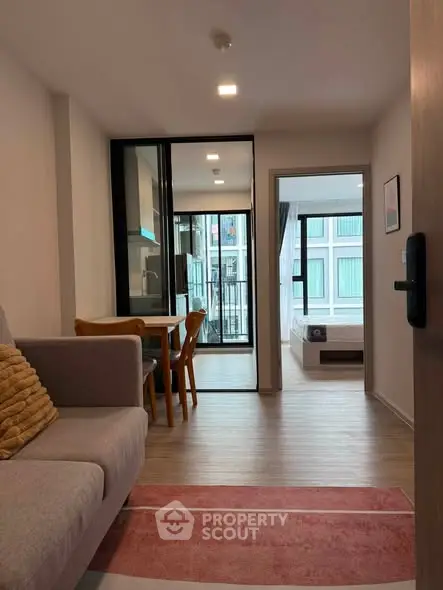 Modern apartment interior with cozy living room and open kitchen layout, featuring a view into the bedroom.