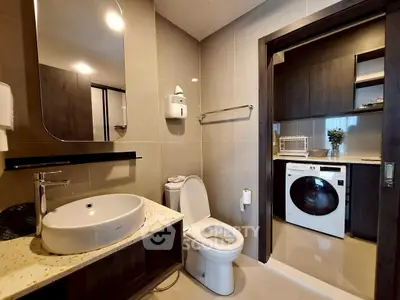Modern bathroom with washing machine and sleek fixtures in a contemporary apartment.