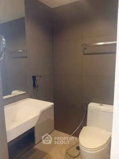 Modern bathroom with sleek fixtures and neutral tones, featuring a toilet and a stylish sink.
