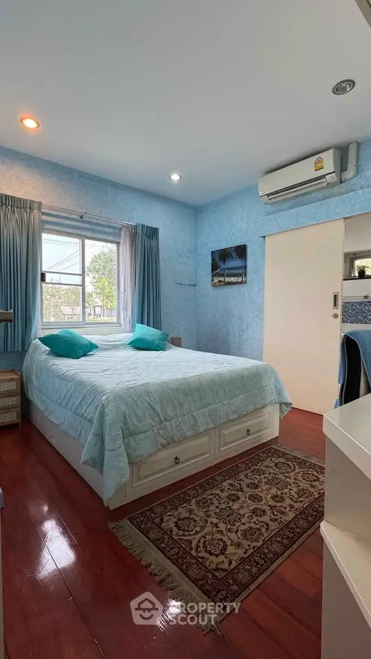 Cozy bedroom with blue walls, wooden flooring, and air conditioning