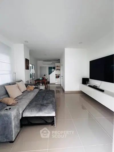 Modern living room with sleek design, large TV, and comfortable gray sofa in a spacious open layout.
