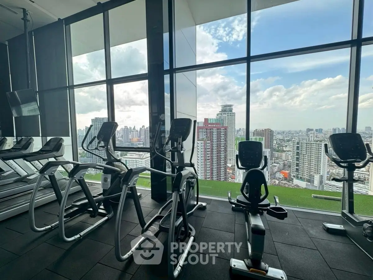 Modern gym with city view and state-of-the-art exercise equipment in high-rise building.