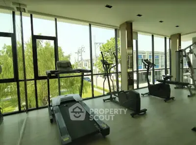 Modern gym with large windows and exercise equipment in a residential building