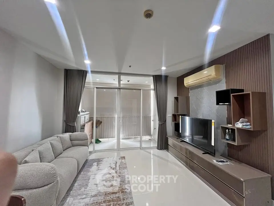 Spacious modern living room with sleek design and large windows leading to a balcony.