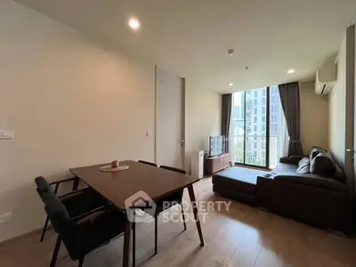 Modern living room with large window and stylish furniture in high-rise apartment.