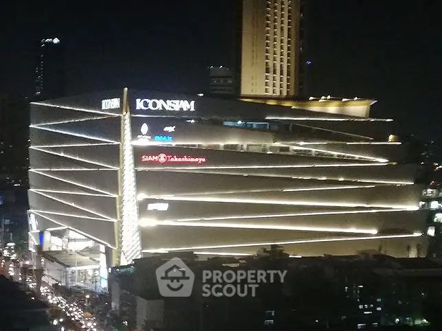 Stunning night view of a modern shopping complex with illuminated facade in a bustling cityscape.