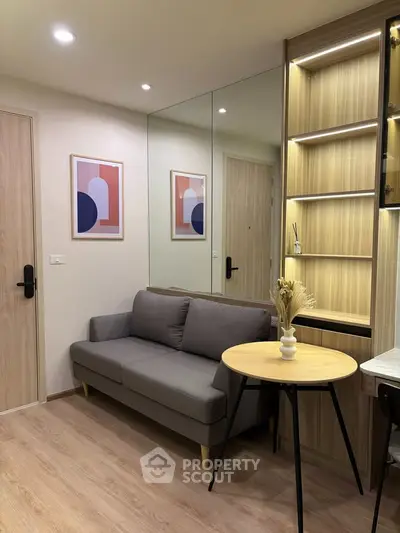 Modern living room with stylish decor, featuring a cozy gray sofa, wooden accents, and contemporary artwork.