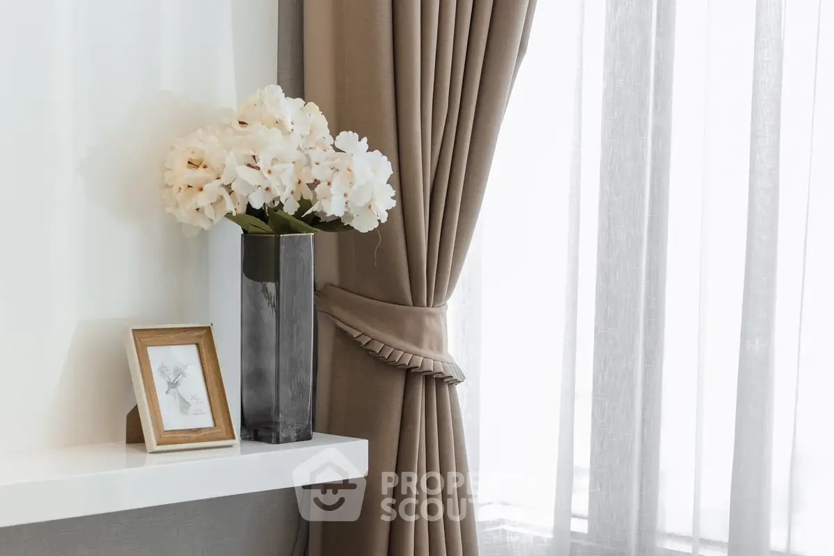 Elegant interior with beige curtains and floral decor on a white shelf, creating a cozy ambiance.