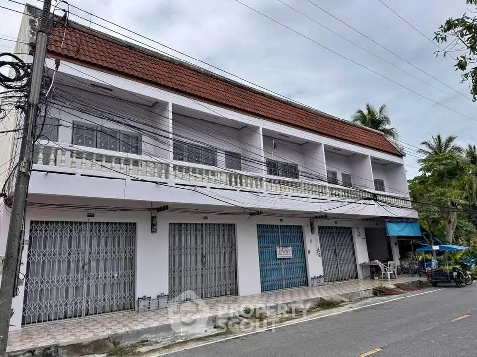 Charming two-story building with tiled roof and spacious balconies, ideal for commercial or residential use.