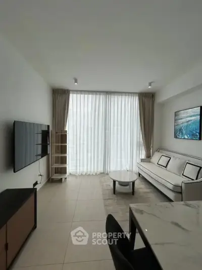 Modern living room with sleek furniture and large windows offering natural light.