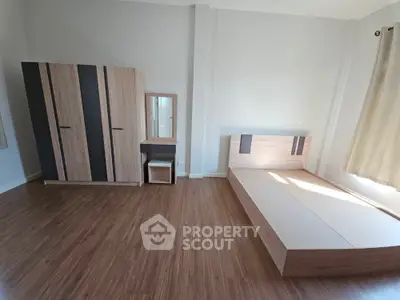 Spacious minimalist bedroom with wooden flooring and modern furniture