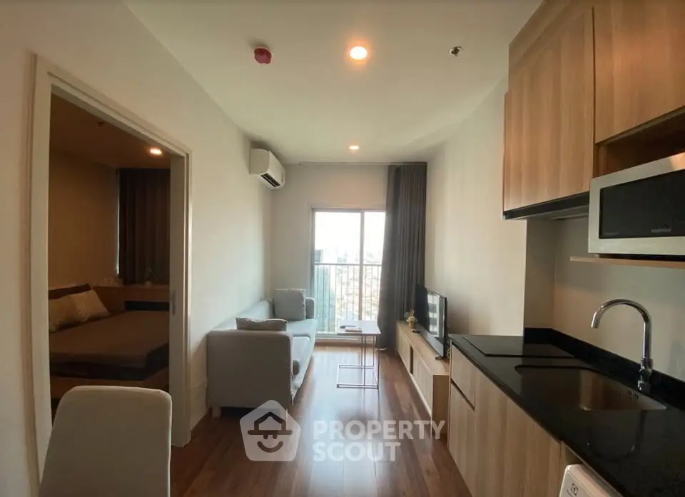 Modern apartment interior with cozy living room and kitchen, featuring wooden flooring and natural light.