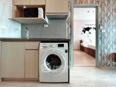Modern kitchen with washing machine and view into a cozy bedroom, perfect for urban living.