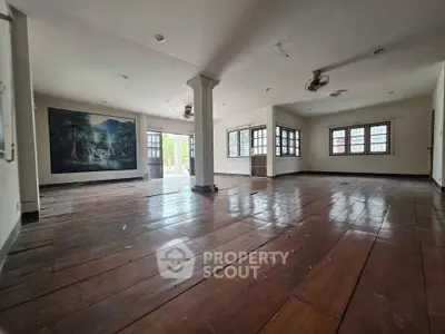 Spacious open-plan living area with wooden flooring and large windows for natural light.