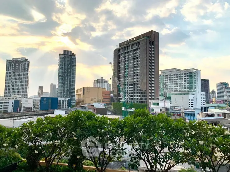 Stunning cityscape view from a high-rise building with lush greenery in the foreground.
