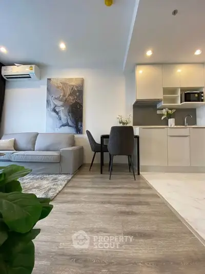 Modern living room with open kitchen, featuring sleek furniture and stylish decor.