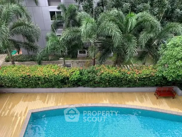 Luxurious residential pool with lush greenery and palm trees, perfect for relaxation and leisure.