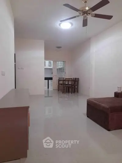 Spacious living room with ceiling fan and dining area in modern apartment.