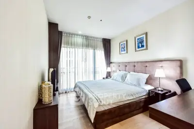 Spacious bedroom with elegant decor and large window offering natural light.