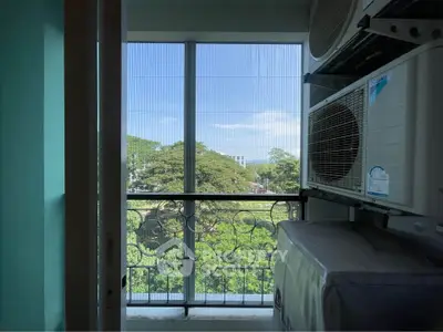 Charming balcony with lush green view and air conditioning units, perfect for relaxation.