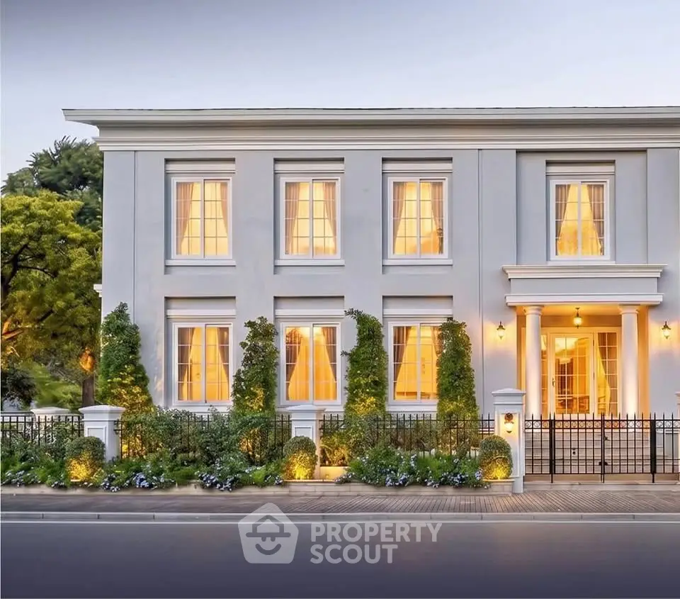 Elegant colonial-style house with lush greenery and warm lighting, showcasing classic architecture and inviting ambiance.