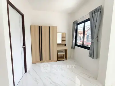 Bright bedroom with modern wardrobe and large window offering natural light.