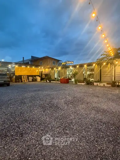 Charming exterior view of a cozy restaurant with warm lighting and ample parking space.