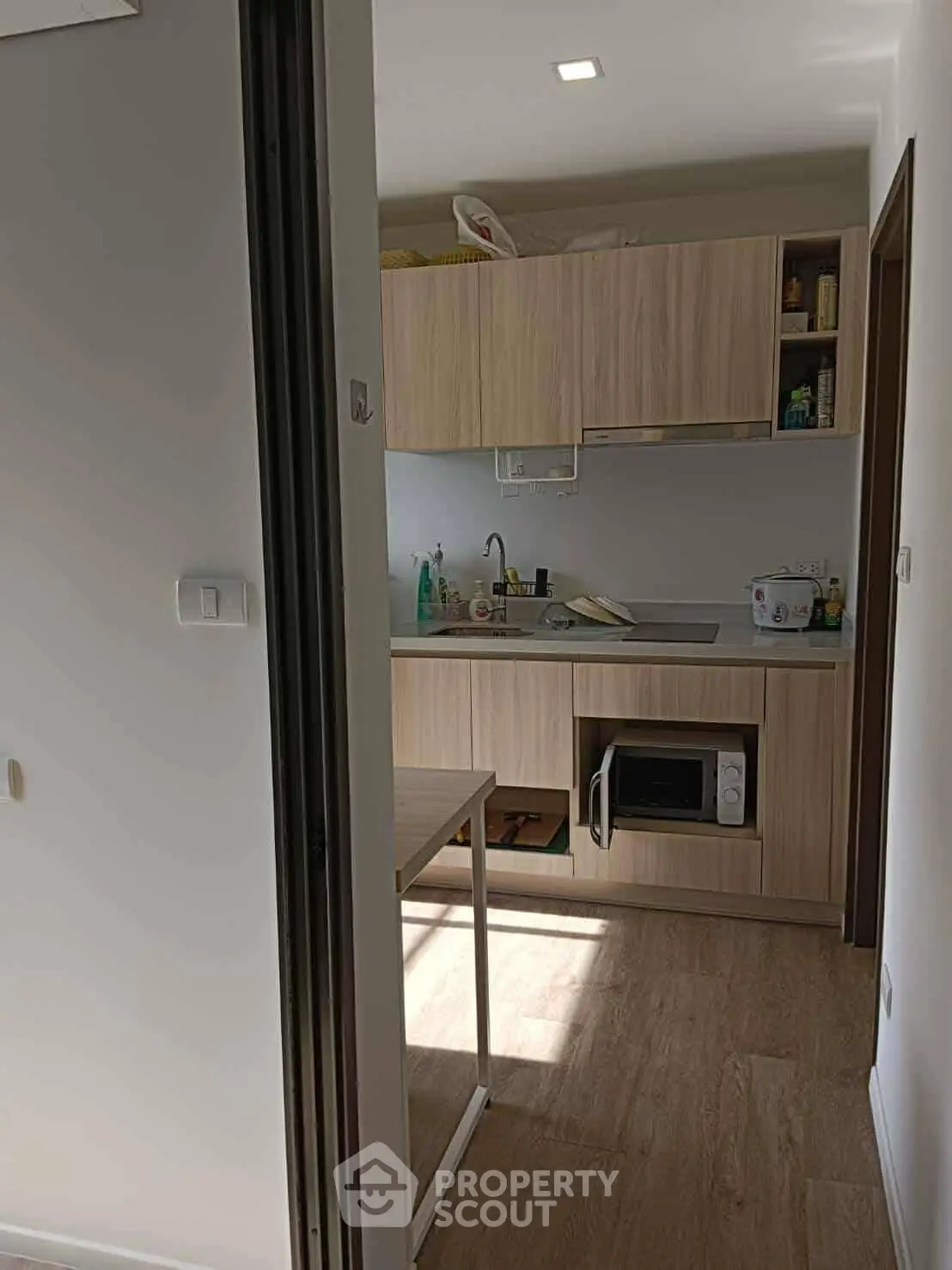 Compact kitchen with modern wooden cabinets and built-in microwave