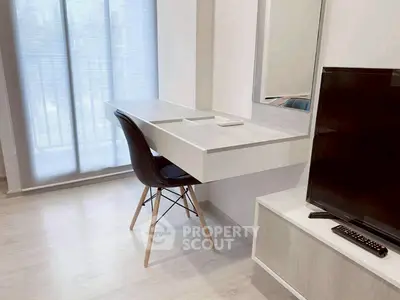 Modern study area with sleek desk and chair next to a flat-screen TV in a bright room.