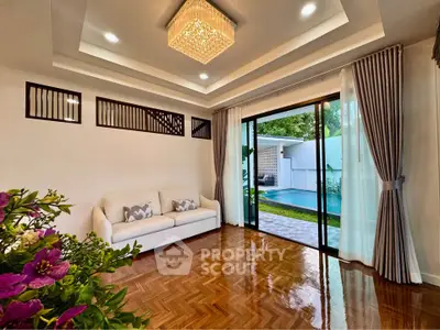 Luxurious living room with pool view, elegant chandelier, and sliding glass doors opening to a serene outdoor space.
