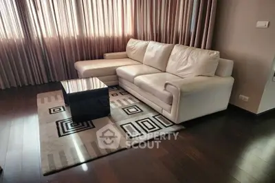 Stylish modern living room with elegant white sofa and geometric rug design.