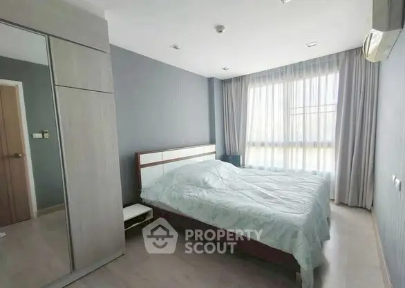 Spacious bedroom with large window and modern furnishings