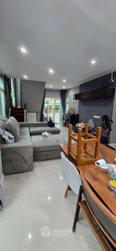 Spacious modern living room with large sofa and dining area, featuring sleek design and ample natural light.