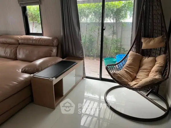 Cozy living room with modern furniture and garden view through sliding glass door.