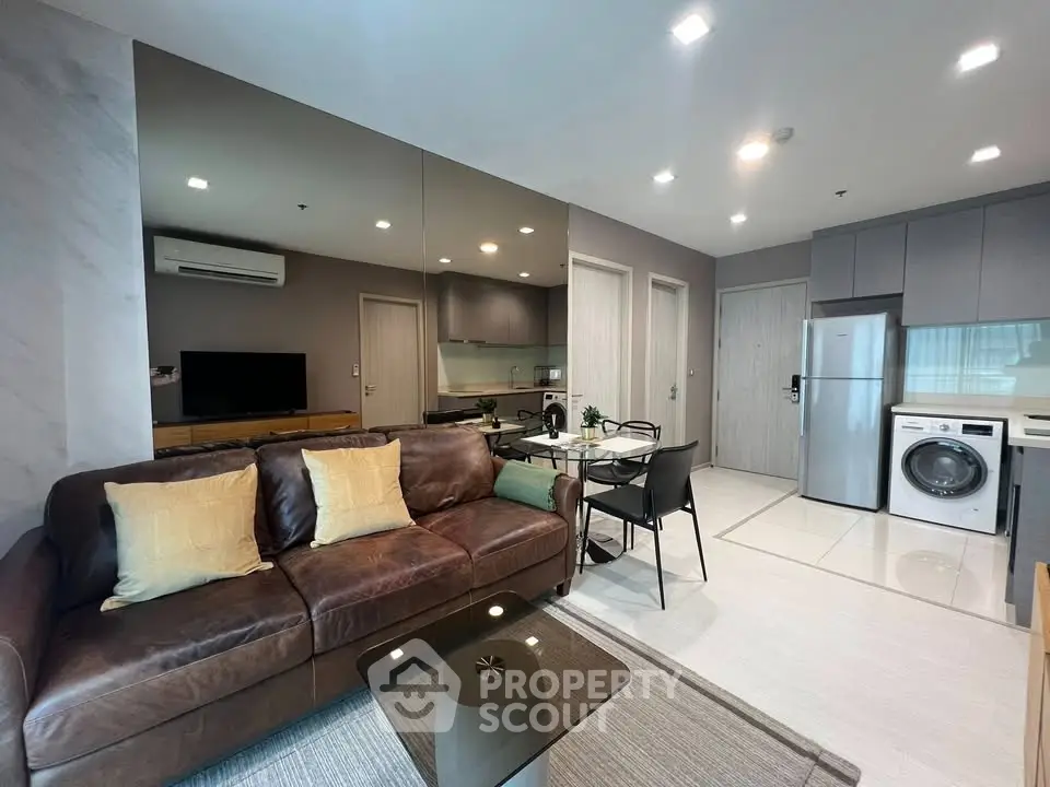 Modern living room with leather sofa, dining area, and integrated kitchen appliances.