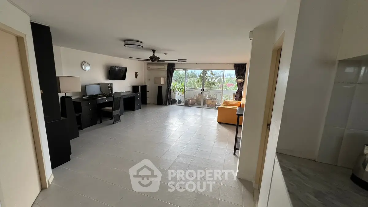 Spacious living room with modern decor and large windows offering natural light and garden view.