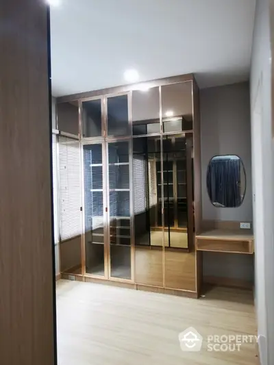 Modern bedroom with sleek mirrored wardrobe and wooden flooring