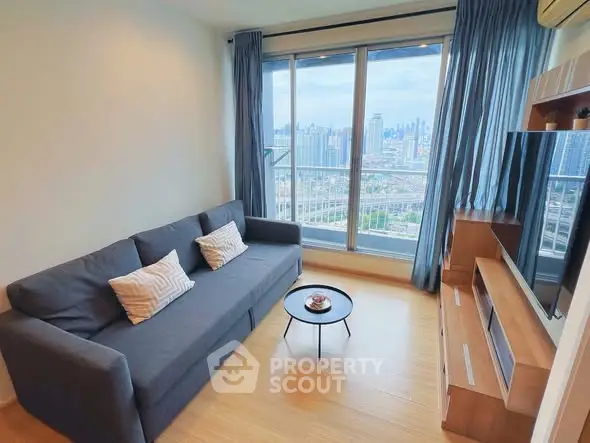 Modern living room with city view, featuring a sleek sofa and entertainment unit.
