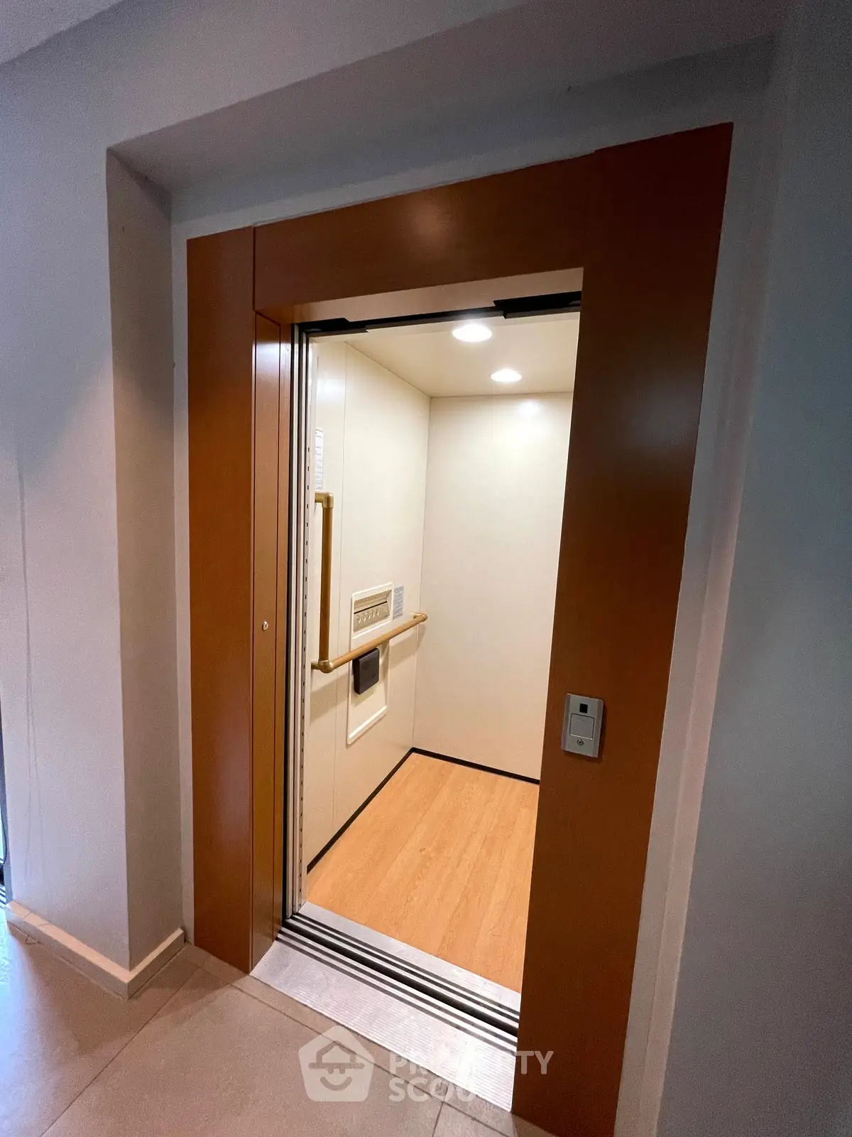 Modern elevator with wooden paneling and bright lighting in a residential building.