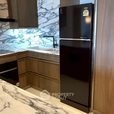 Modern kitchen with marble countertops and sleek black fridge