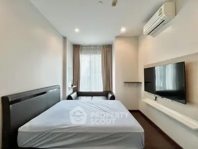 Modern bedroom with air conditioning and wall-mounted TV, featuring a large window for natural light.